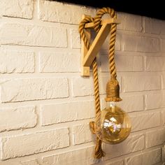 a light bulb hanging from the side of a white brick wall next to a rope