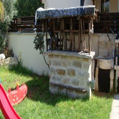 an old stone building with tools on the roof and some grass in front of it