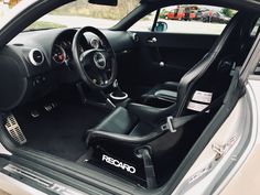 the interior of a sports car with its door open and steering wheel in position on the floor