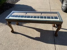 a piano bench sitting on the sidewalk in front of a car