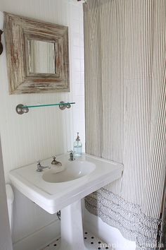 a white sink sitting under a bathroom mirror next to a shower curtain in a bathroom