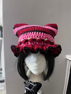 a mannequin head wearing a crocheted hat with black and pink trim