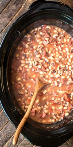 a wooden spoon in a slow cooker filled with beans