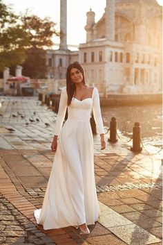 a woman in a white dress is walking down the street with her hand on her hip