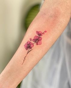 a small pink flower tattoo on the arm