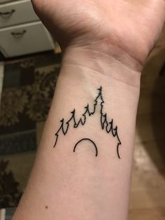 a hand with a wrist tattoo that has mountains on it