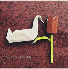 two origami birds sitting on the ground next to each other