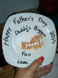 a person holding a plate with writing on it that says happy father's day daddy's biggest fan love