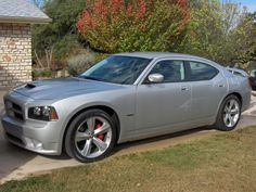 a silver dodge charger parked in front of a brick building on the side of a road