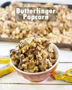 a bowl full of butterfingered popcorn sitting on top of a table next to some candy bars