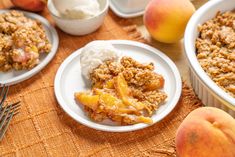 two white plates topped with food next to peaches