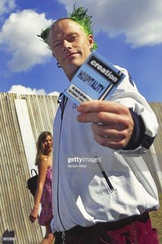 a man with green hair pointing at the camera