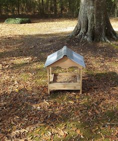 a bird feeder in the middle of leaves under a tree with a blue tin roof