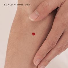 a small red heart tattoo on the side of a man's right arm and leg