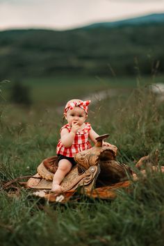 a small child sitting on top of a piece of wood in the middle of a field