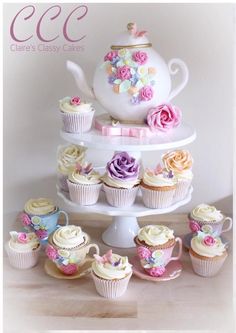 there are cupcakes and tea cups on the cake platter, all decorated in pastel colors