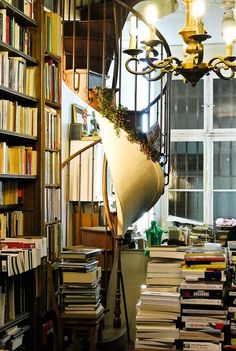 a room filled with lots of books next to a chandelier