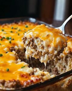 a casserole dish with meat and cheese being lifted from the casserole