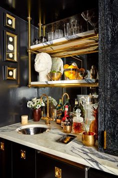 a kitchen with marble counter tops and gold accents on the shelves, along with brass faucets