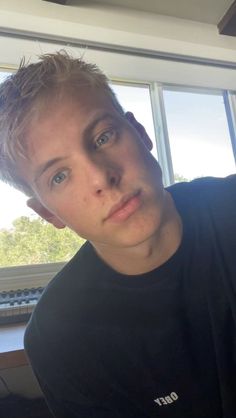 a young man sitting in front of a window