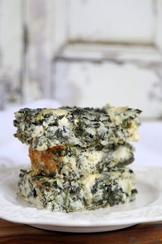 two pieces of spinach and cheese on a white plate with a wooden table in the background