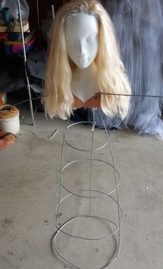 a white mannequin head sitting on top of a metal wire stand with hair hanging from it's sides