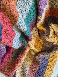 a multicolored crocheted blanket laying on top of a bed