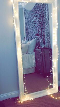 a mirror that has lights on it in a room with a bed and suitcases