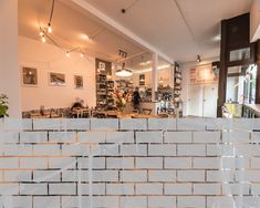 the interior of a coffee shop with white bricks on the wall and people in the background