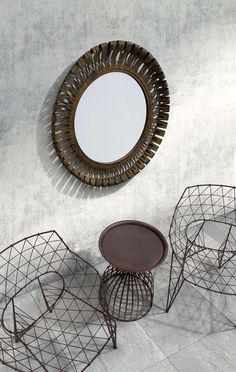 three metal chairs and a round mirror on the wall