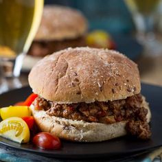 two hamburgers with meat and vegetables on a black plate