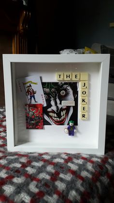 a shadow box with scrabbles in the shape of joker's face