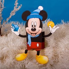 a mickey mouse figurine is posed in front of some frosted trees and bushes