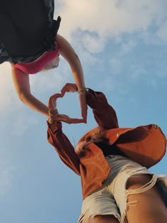 a woman standing on top of a wooden pole with her hands in the shape of a heart