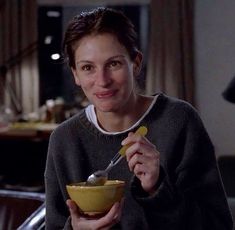 a woman holding a bowl and spoon in her hand