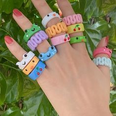 a person's hand with five different colored rings on their fingers and one has an emoticive smiley face