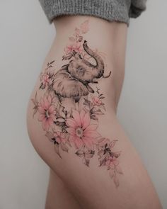 an elephant and flowers tattoo on the side of a woman's thigh, with pink flowers