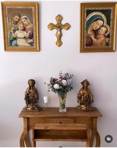 two paintings on the wall above a wooden table with flowers and candles in front of it