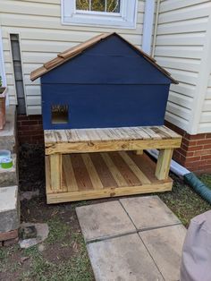 a dog house made out of pallets and wood with a blue roof on top