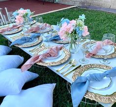 a table set up with blue and gold plates, napkins and flowers in vases