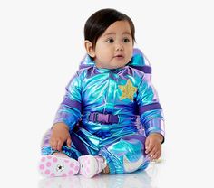 a baby sitting on the floor wearing a shiny blue outfit