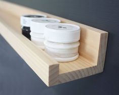 three jars sitting on top of a wooden shelf