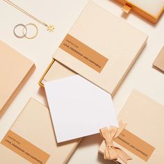 an assortment of business cards, envelopes and rings on a white surface with gold accents