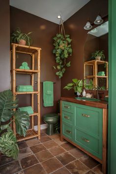 A brown bathroom design with green accents, including plants and a green vanity for a natural, earthy look. Brown And Green Bathroom, Bathroom Aesthetics, Brown And Green