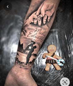 a person with a tattoo on their arm holding a small gingerbread man's hand