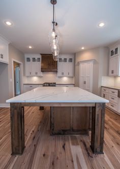 a kitchen with an island in the middle of it and lights hanging from the ceiling