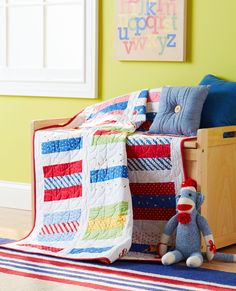 a child's bedroom with green walls and colorful quilted bedspread on the bed