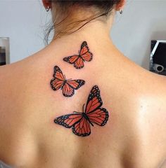 the back of a woman's neck with three orange butterflies on her left shoulder