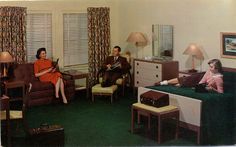 two people sitting on couches in a living room with green carpeted flooring