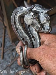 a person holding two metal horse heads in their hand